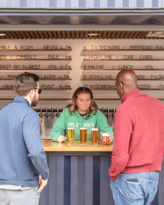 Bartender pouring craft beer at the shipping container tap wall